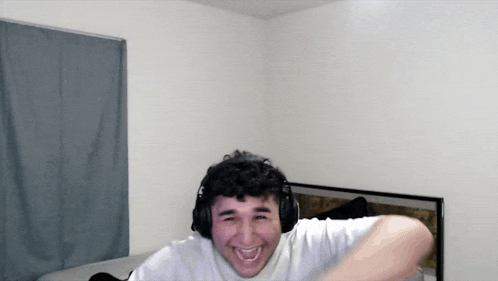 a man wearing headphones and a white shirt is laughing
