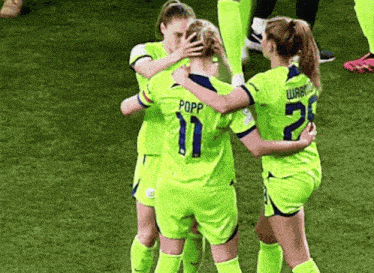 a group of female soccer players are hugging each other and one of them has the number 11 on her jersey