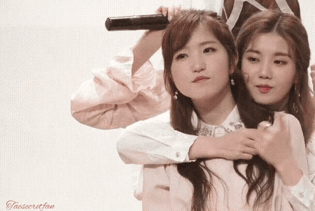 two girls are hugging each other and one has a microphone in her hair
