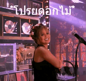 a woman in a black dress is standing in front of a microphone in a room with a purple background .