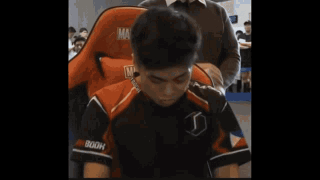 a man is sitting in a chair with a shirt that says gdh on it