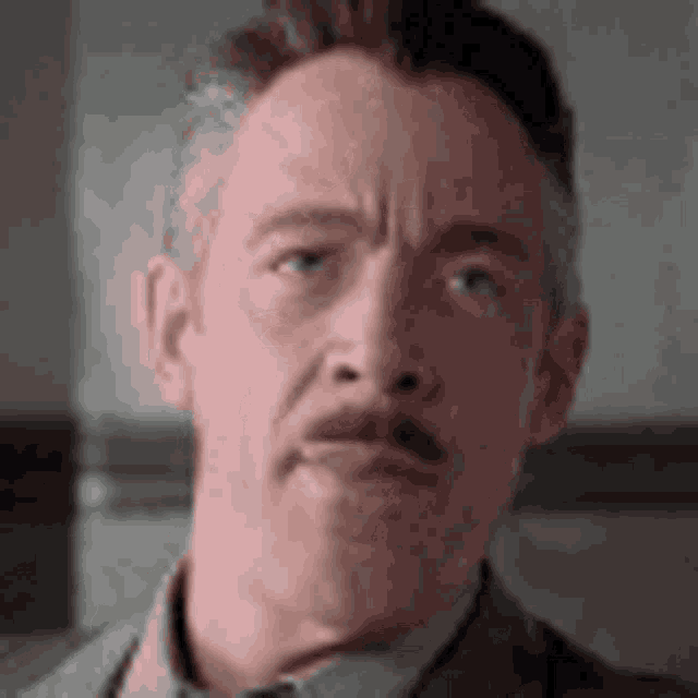 a man with a mustache is making a funny face .