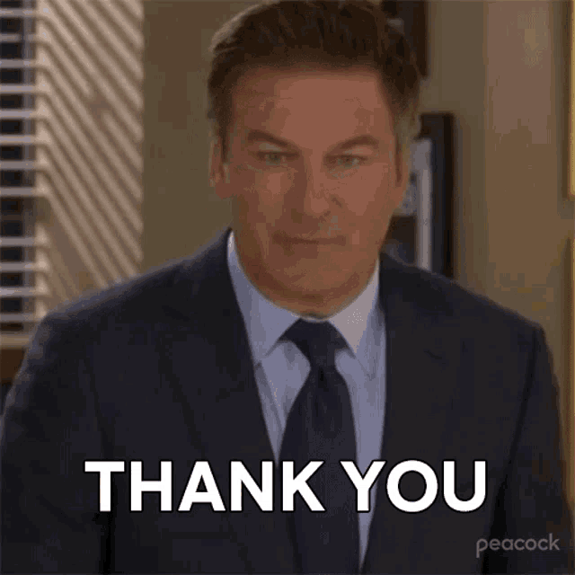 a man in a suit and tie is making a thank you gesture .