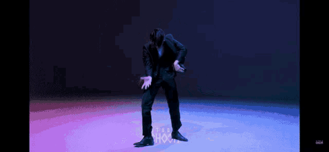 a man in a suit is dancing in front of a purple and blue background that says ' i love you '