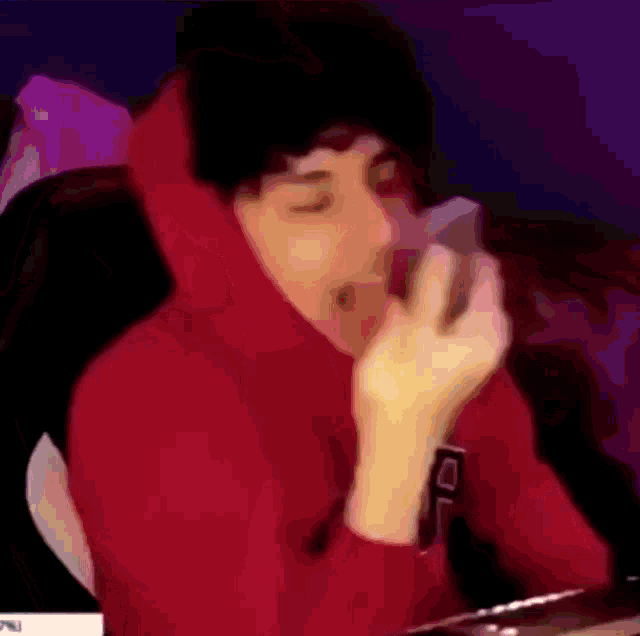 a man in a red hoodie is holding a cell phone in his hand