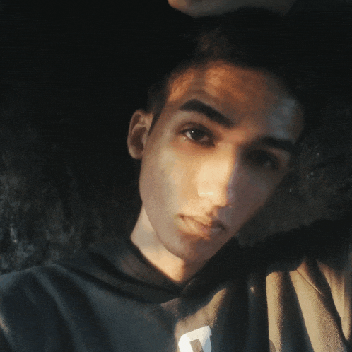 a young man wearing a black sweatshirt with the letter t on it
