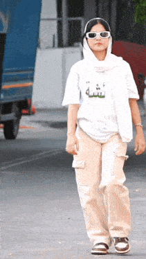 a woman wearing sunglasses and a white t-shirt with arabic writing on it