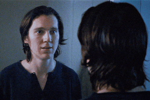 two men are looking at each other in a dark room