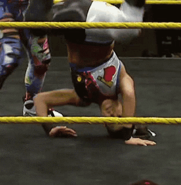 a wrestler doing a handstand in a wrestling ring