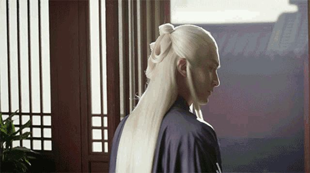 a man with long white hair is standing in a room