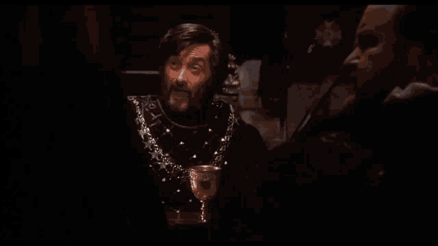 a man with a beard is sitting in a dark room with the words wooooowee !!! written on the screen