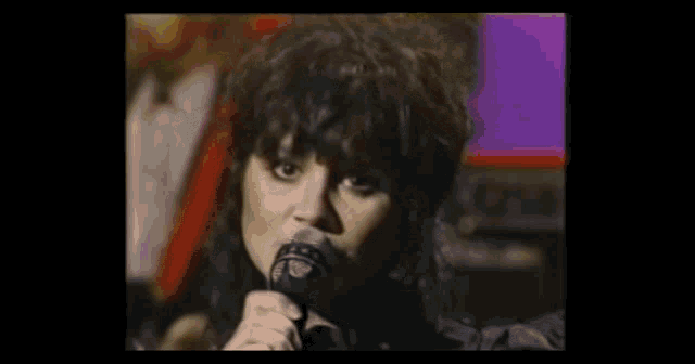 a woman is singing into a microphone in a dark room