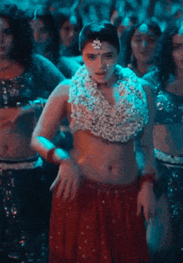a woman in a red skirt and white top is dancing in front of a crowd of people .