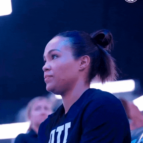 a woman wearing a blue shirt with the word utl on it is sitting in a stadium .