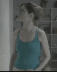 a woman in a blue tank top is standing in front of a wall .