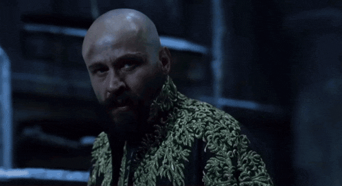 a bald man with a beard is wearing a gold embroidered coat