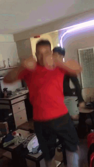 a man in a red shirt dancing in a living room