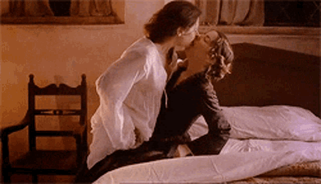 two women kissing on a bed in a bedroom