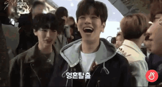 a group of people are laughing in a crowd and one of them has korean writing on his face .