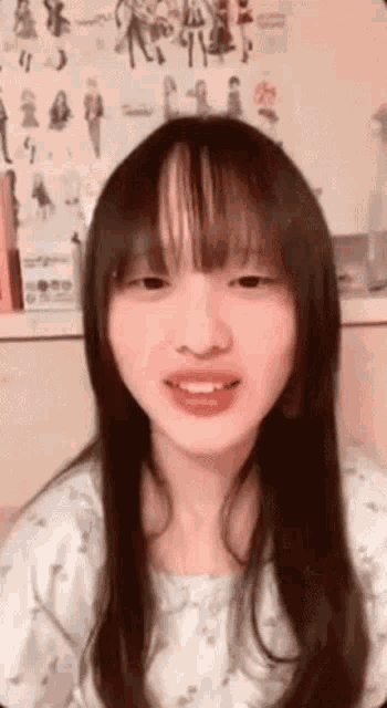 a girl with long hair and bangs looks at the camera and smiles .