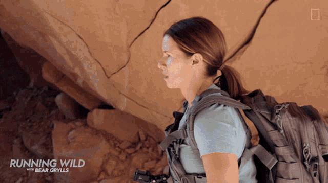 a woman with a backpack is on a running wild with bear grylls ad