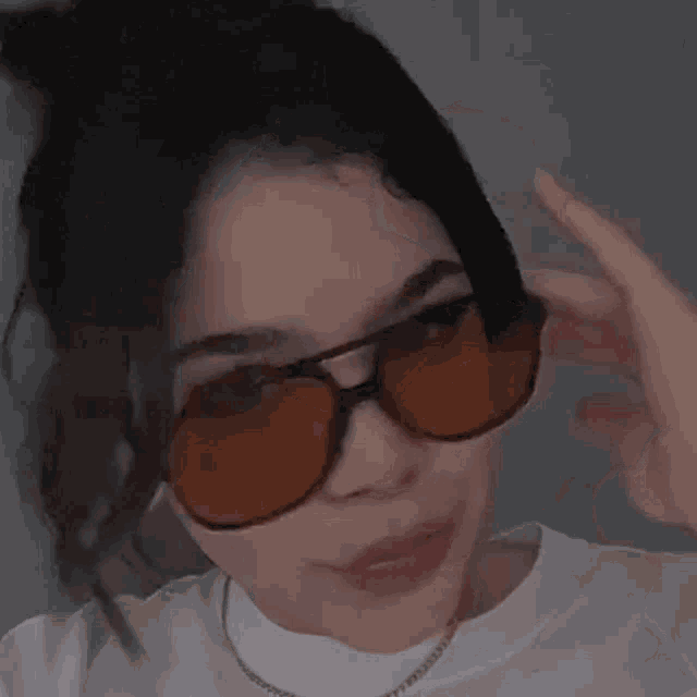 a woman wearing sunglasses is making a funny face .