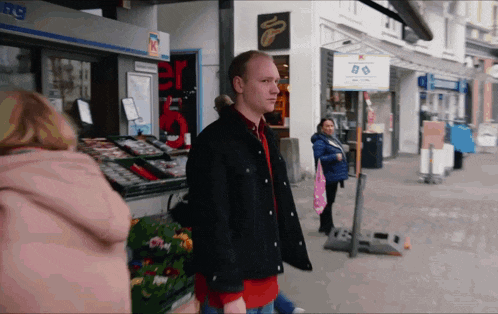 a man in a black jacket stands in front of a store that says ' a ' on the front