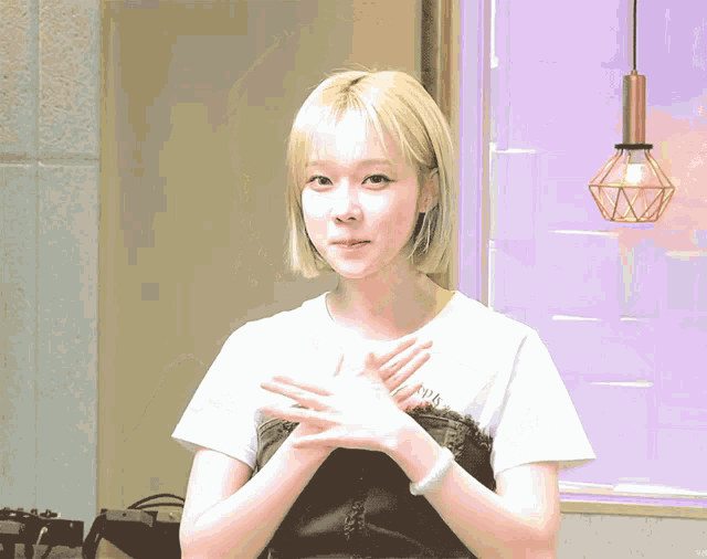 a woman with blonde hair is wearing a white t-shirt with a black top underneath it