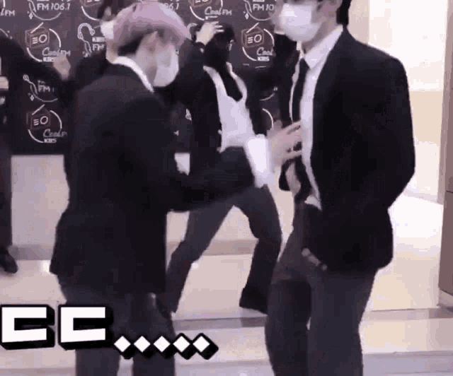 a group of men in suits and face masks are dancing in front of a sign that says fm 106.7