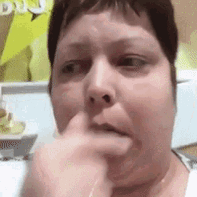 a close up of a woman 's face with her hand on her chin .