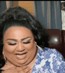 a woman wearing a blue and white floral shirt laughs