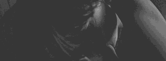 a black and white photo of a woman kissing a man 's face .