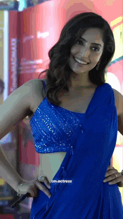 a woman wearing a blue crop top and a blue saree smiles for the camera