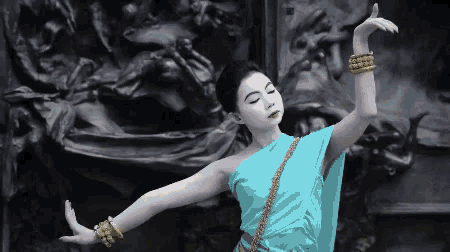 a woman in a blue dress with gold bracelets on her wrists
