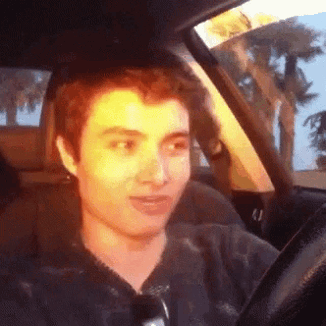 a young man is driving a car and making a funny face