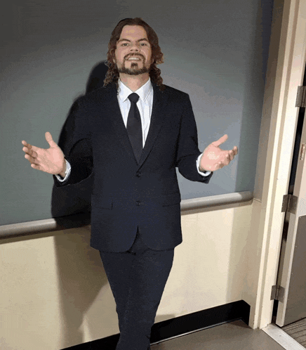 a man in a suit and tie stands in front of a door
