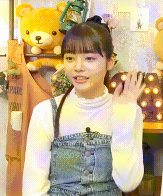 a girl in overalls is standing in front of a teddy bear and a lantern .