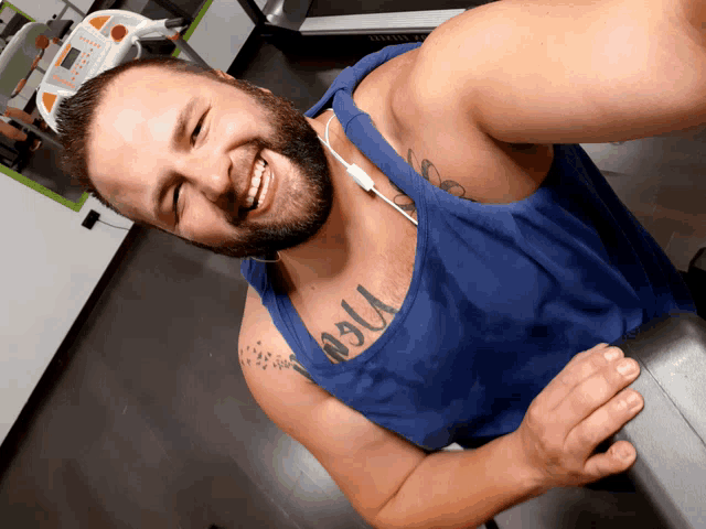 a man wearing a blue tank top has a tattoo on his chest that says ' jesus '