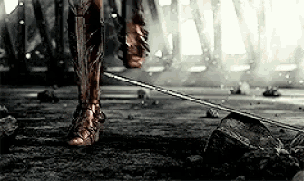 a close up of a person 's leg holding a sword in a dark room .