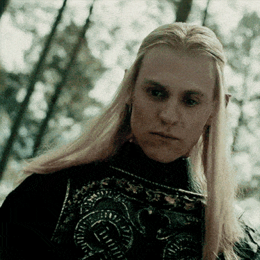 a close up of a man with long blonde hair and a black shirt