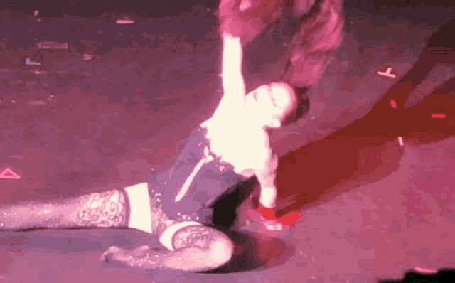 a woman is laying on the floor on a stage in a dark room with purple lights .