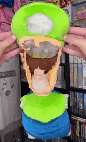 a person is holding a green mushroom with the word pikmin on a white shirt in the background