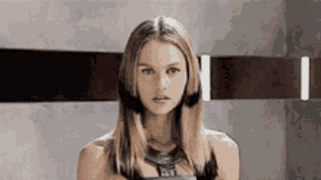 a woman with long hair is standing in front of a wall .