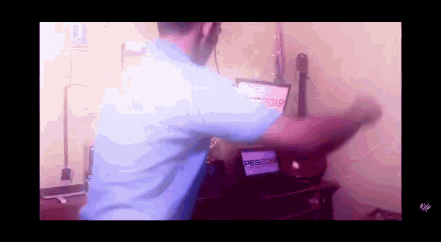 a man in a blue shirt is dancing in front of a computer screen that says pes 2018 .