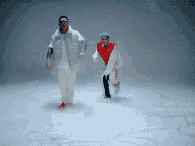a man in a white vest and a man in a red shirt are dancing together