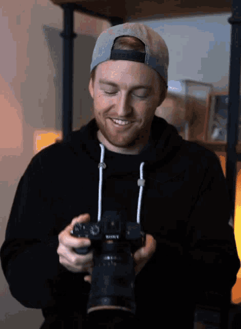 a man holding a sony camera with his eyes closed