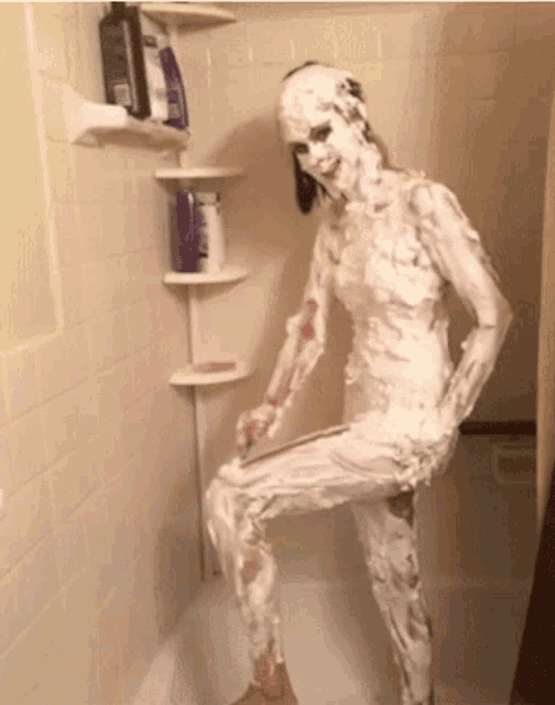 a woman covered in shaving cream stands in a shower