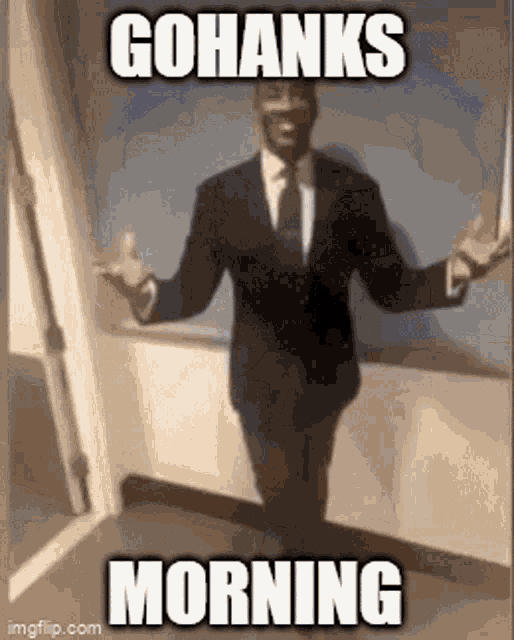 a man in a suit and tie is standing in front of a window and says gohanks morning