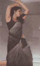 a woman in a saree is dancing in the rain .