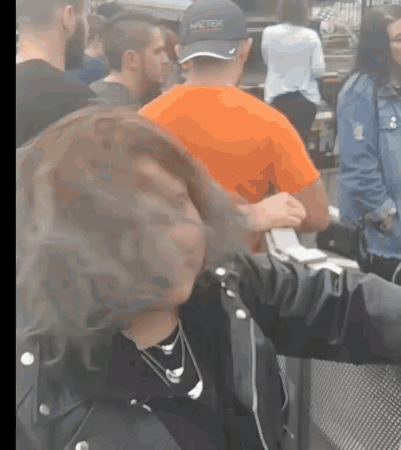 a man wearing a hat that says niketek stands in a crowd of people